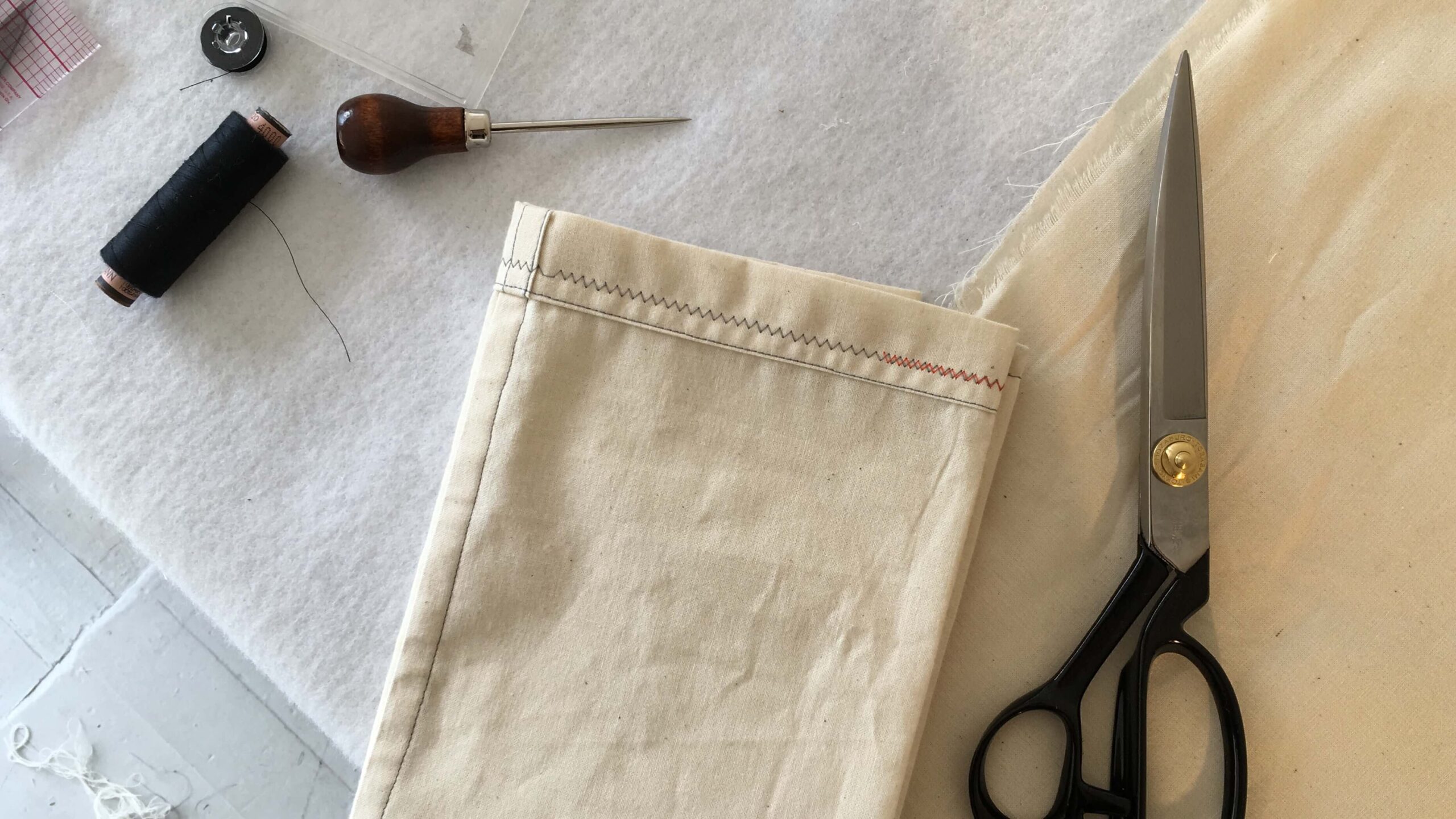image of table with fabric scissors, sewing canvas, thread and tool
